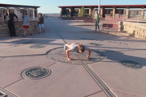Katie pretends like she exercises doing a push up at Four Corners.  